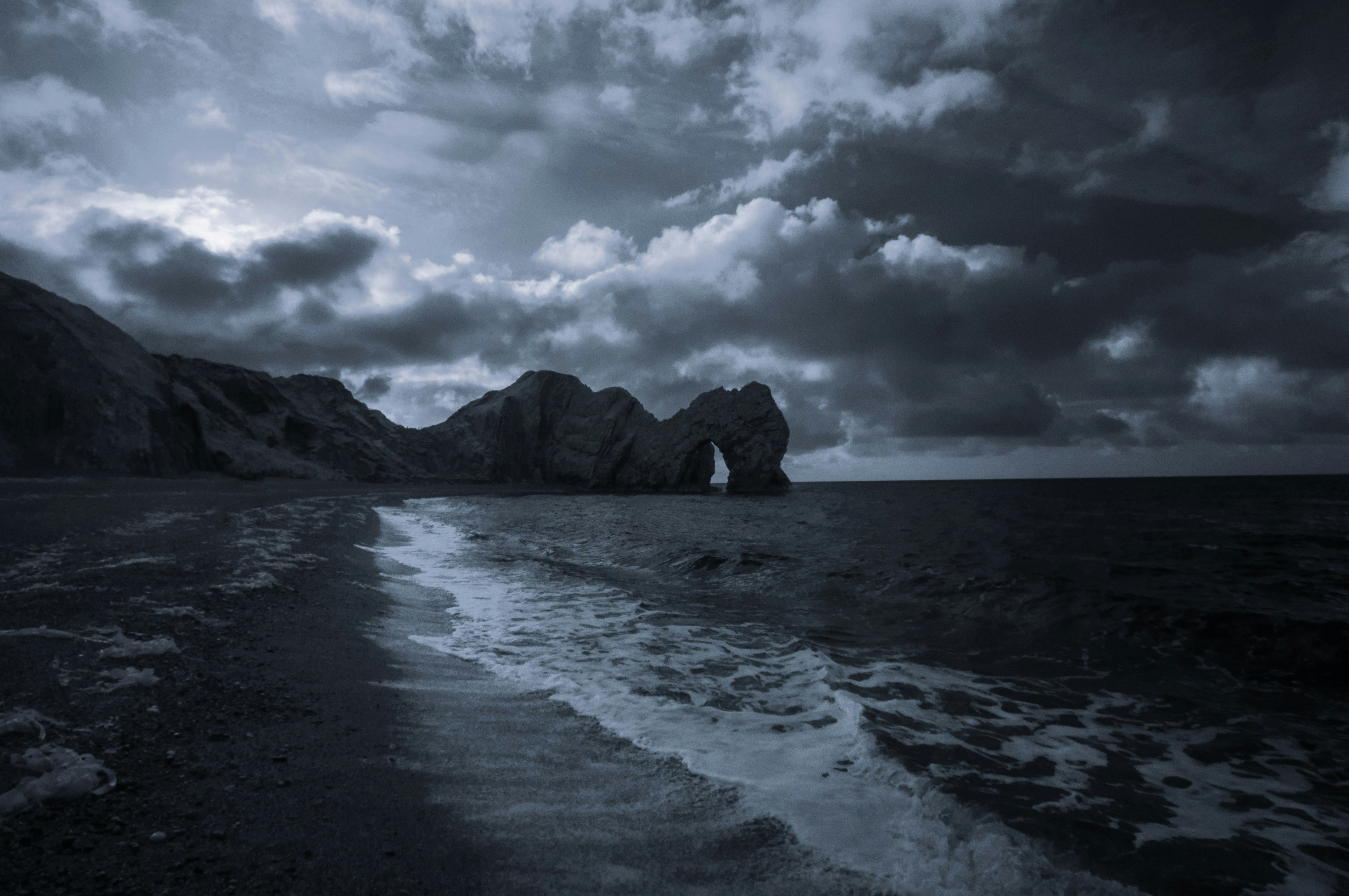 body of water near rock formation during night time